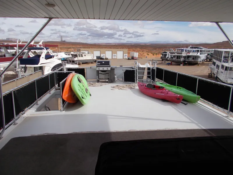 Slide: The Image of Bravada Tranquility Trip 17 houseboat deck with kayaks and grill, docked at marina. - 14