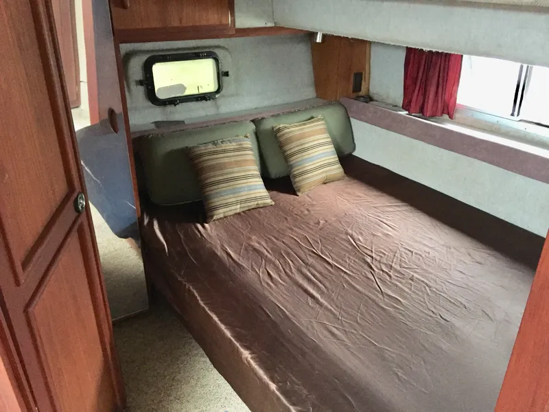 Slide: The Image of 1986 Cruisers Yachts 336 Ultra Vee cabin interior with bed and striped pillows. - 14