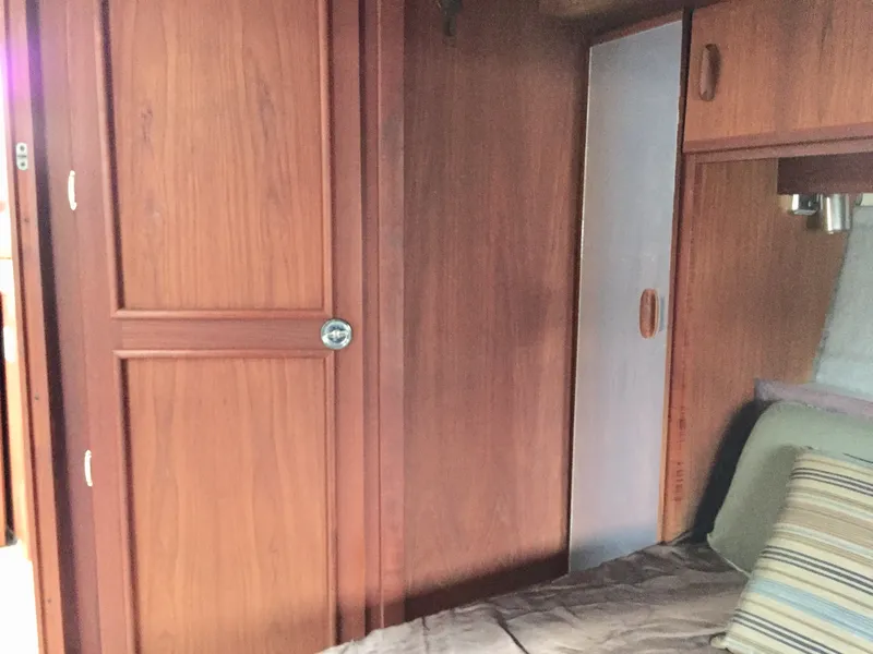 Slide: The Image of 1986 Cruisers Yachts 336 Ultra Vee cabin interior with wooden paneling and cozy bedding. - 15