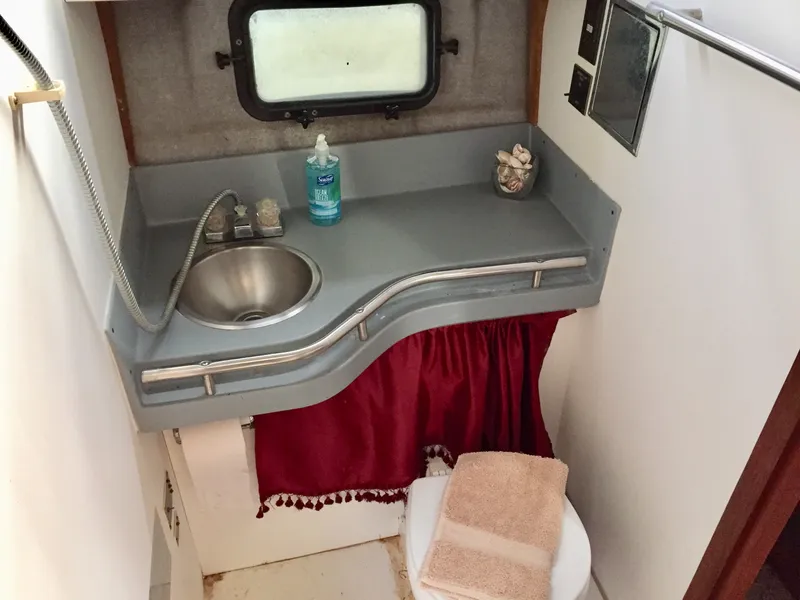 Slide: The Image of 1986 Cruisers Yachts 336 Ultra Vee bathroom with sink, window, and red curtain. - 16