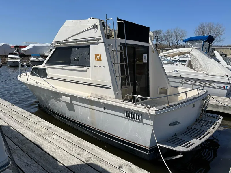 Slide: The Image of 1980 Trojan F-30 Flybridge Sedan docked at marina, side view. - 1