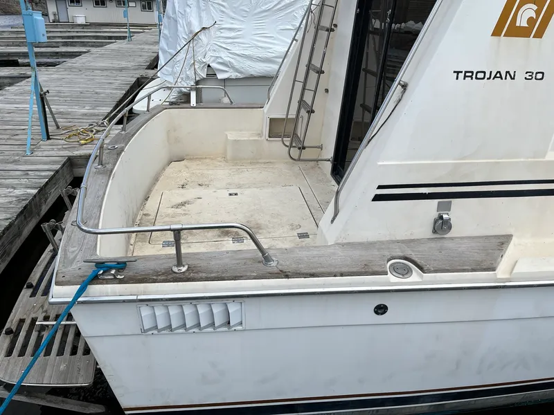 Slide: The Image of 1980 Trojan F-30 Flybridge Sedan boat docked, showing rear deck and railing. - 2