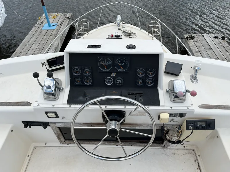 Slide: The Image of 1980 Trojan F-30 Flybridge Sedan helm with steering wheel, gauges, and controls at dock. - 3