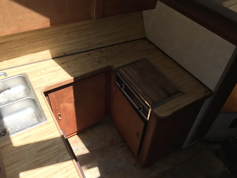Slide: The Image of 1980 Trojan F-30 Flybridge Sedan kitchen area with wooden cabinets and dual sink. - 7