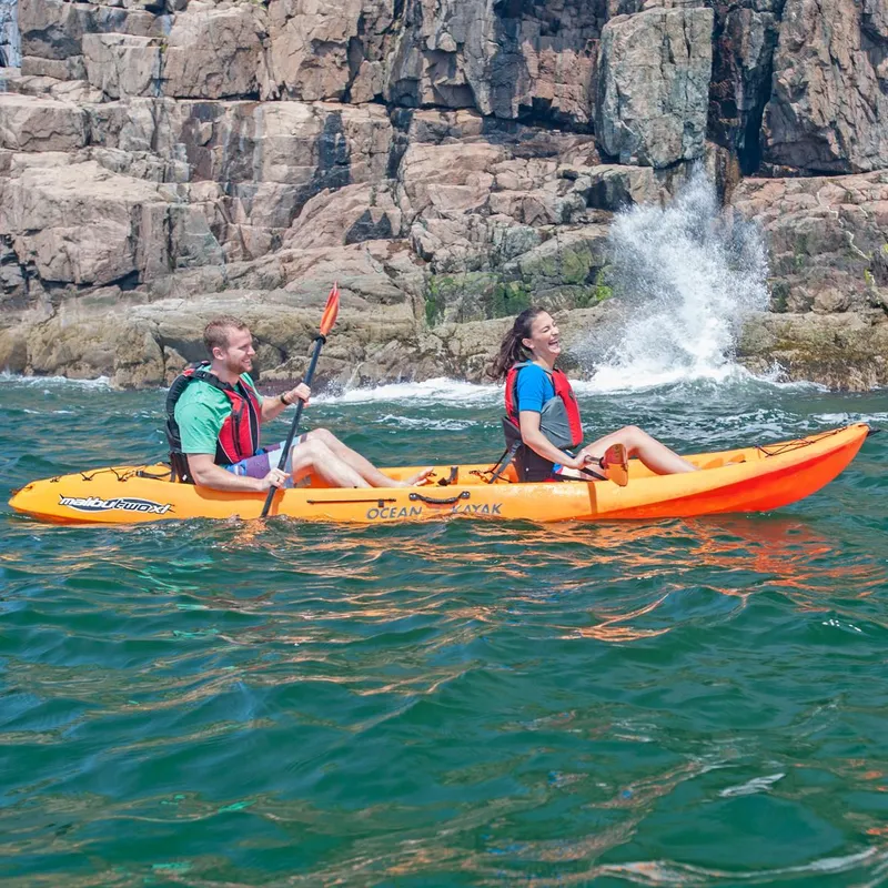 The Image of Two people kayaking in an Ocean Kayak Malibu Two XL near rocky cliffs, 2023 model. - 0