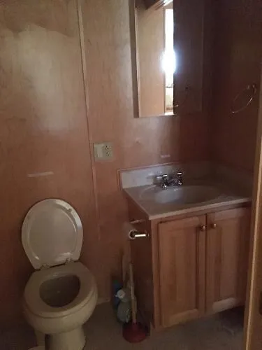 Slide: The Image of Small bathroom with wooden cabinets, sink, and toilet in a 2002 Sharpe Just Because Trip 33. - 18