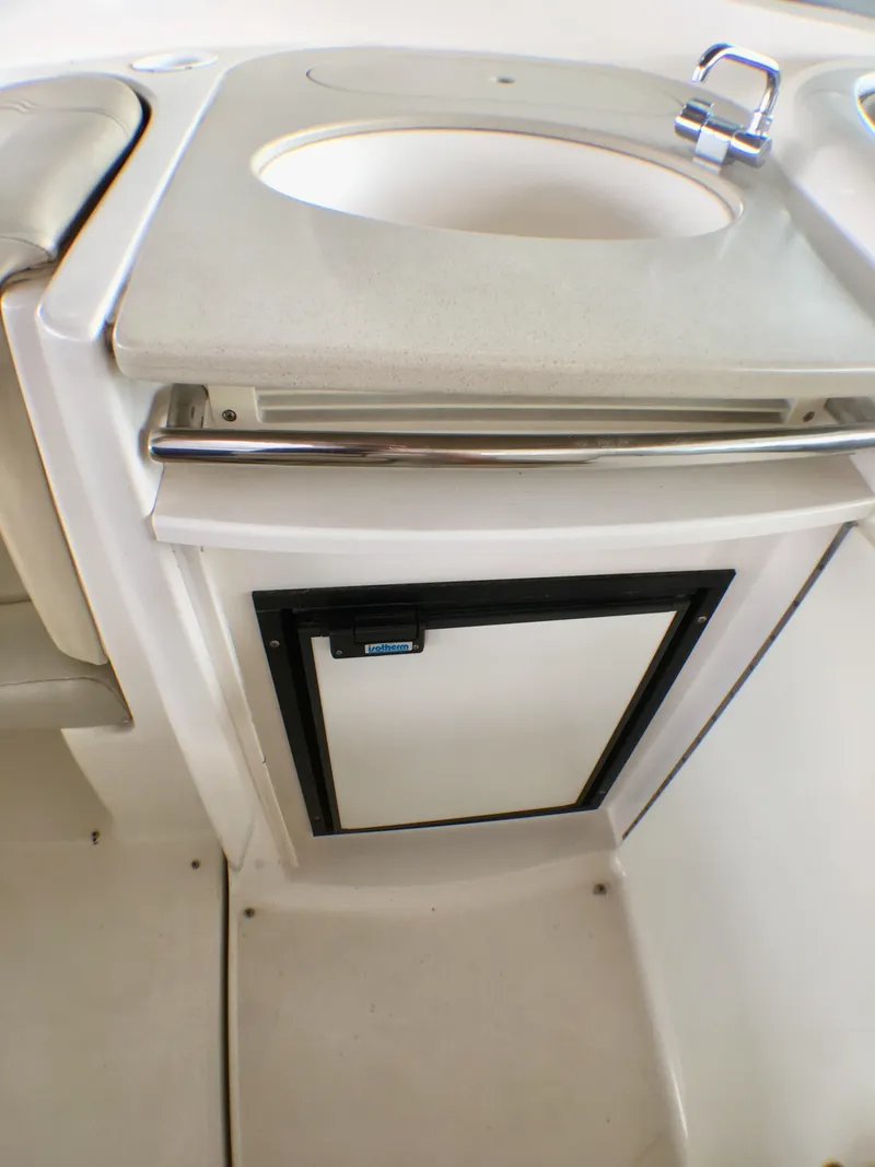 Slide: The Image of The cabin of a 2003 Chaparral Signature 320 features a compact kitchenette with a sink and fridge. - 17