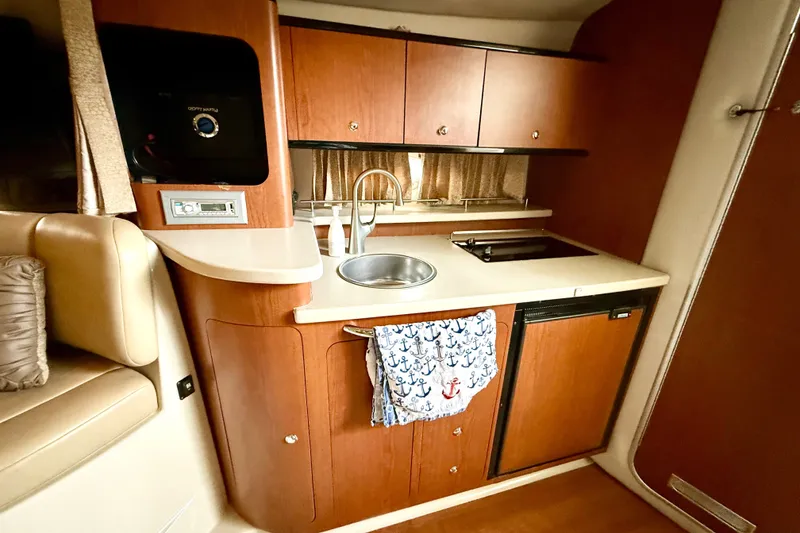 Slide: The Image of 2003 Chaparral Signature 320 boat kitchen with wood cabinets, sink, and stove. - 14