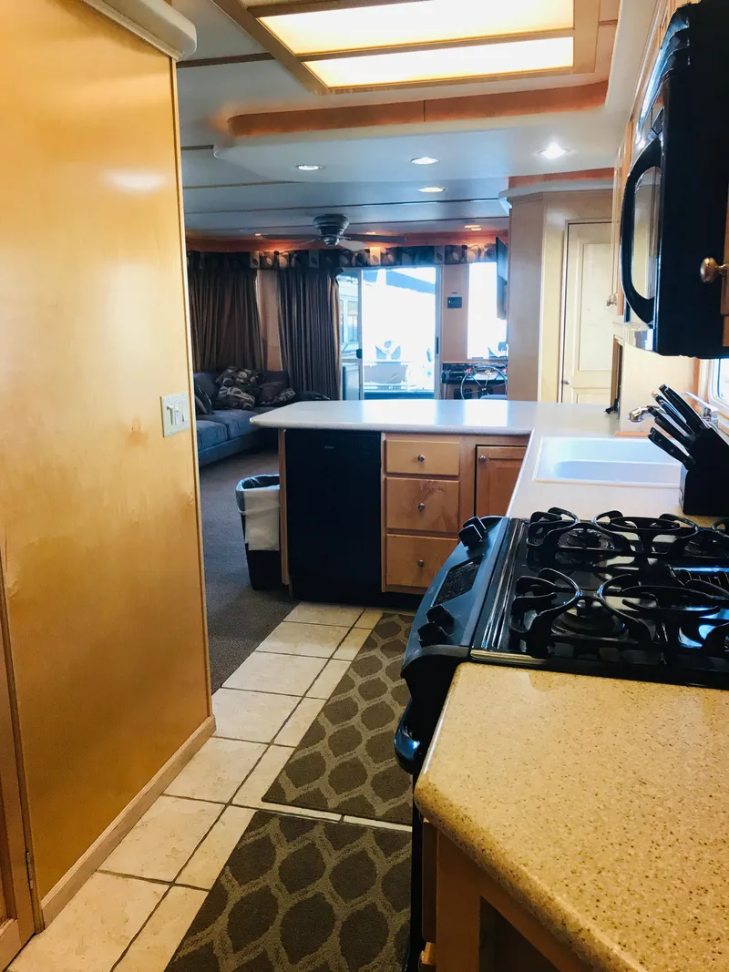 Slide: The Image of 2005 Stardust Cruisers houseboat kitchen with stove, countertops, and cozy living area. - 13