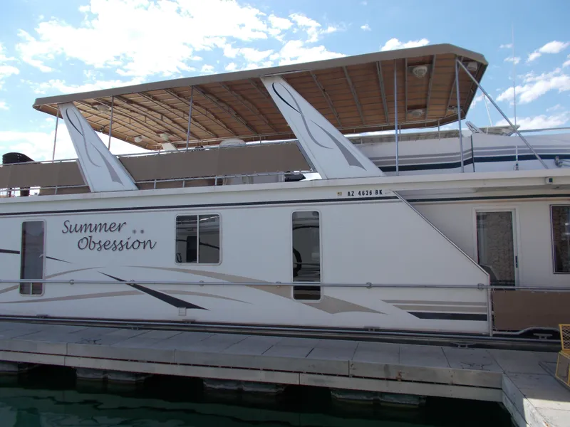 Slide: The Image of 2005 Stardust Cruisers Summer Obsession houseboat docked under a clear blue sky. - 2