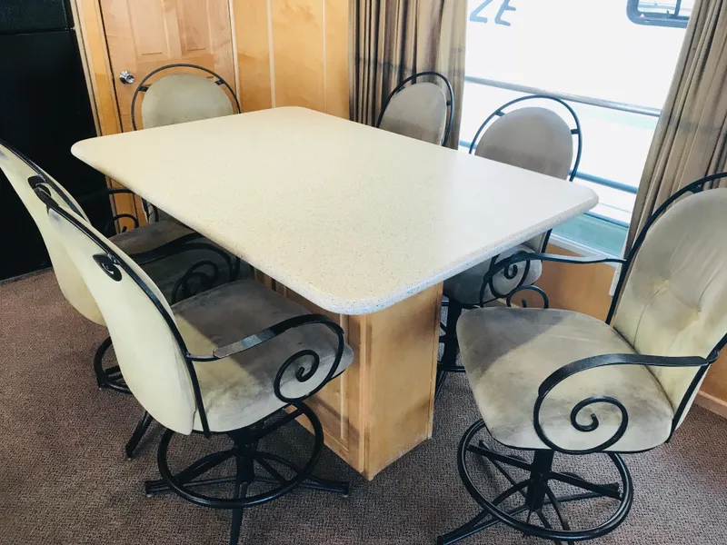 Slide: The Image of Dining area with six cushioned chairs and a rectangular table in a 2005 Stardust Cruisers houseboat. - 9