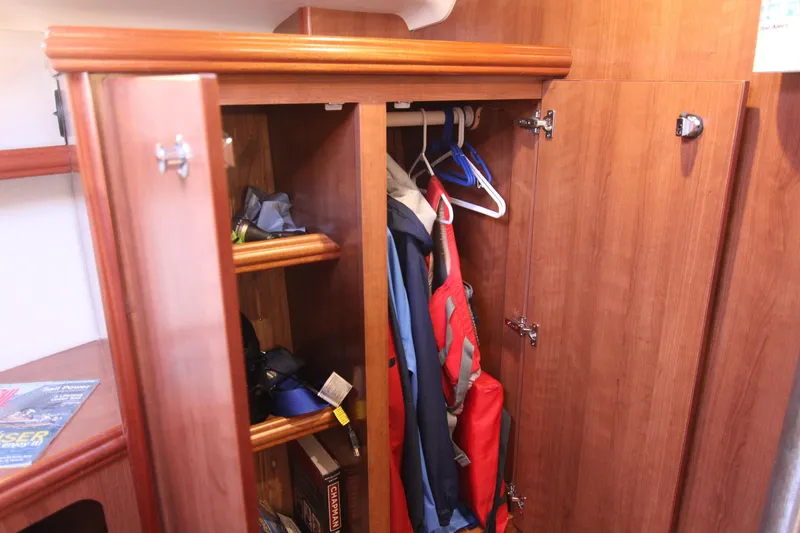 Slide: The Image of An open wooden closet with clothes and shelves inside a 2015 Marlow-Hunter 37. - 49