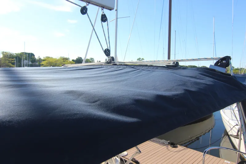 Slide: The Image of A sailboat with a dark blue cover at the dock, surrounded by other boats and clear sky. - 19