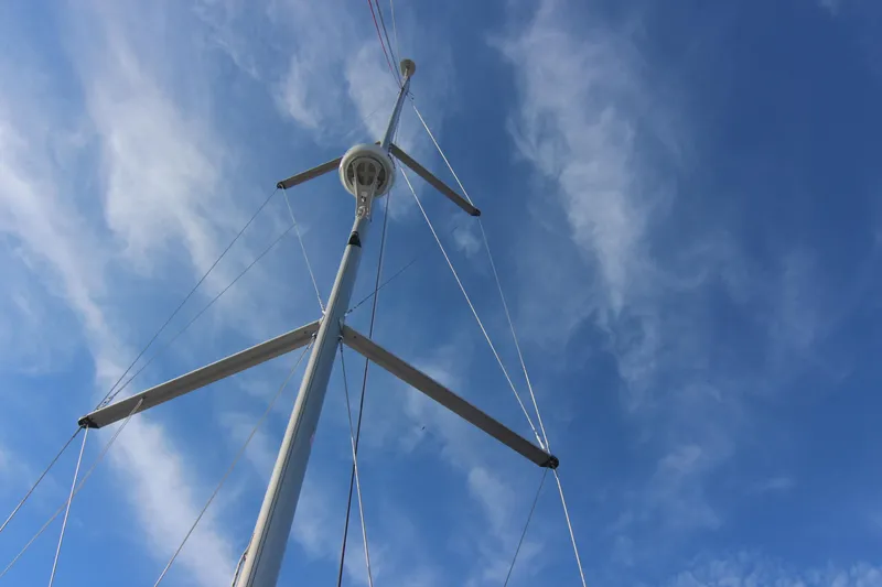Slide: The Image of The mast of a sailboat extends into the blue sky with light clouds. - 13