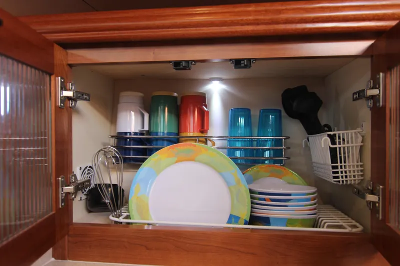 Slide: The Image of A cabinet with colorful dishes and glasses, neatly stacked, inside a boat. - 37
