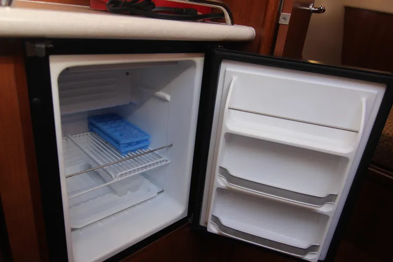 Slide: The Image of An open fridge in a boat cabin with a blue ice tray inside. - 33