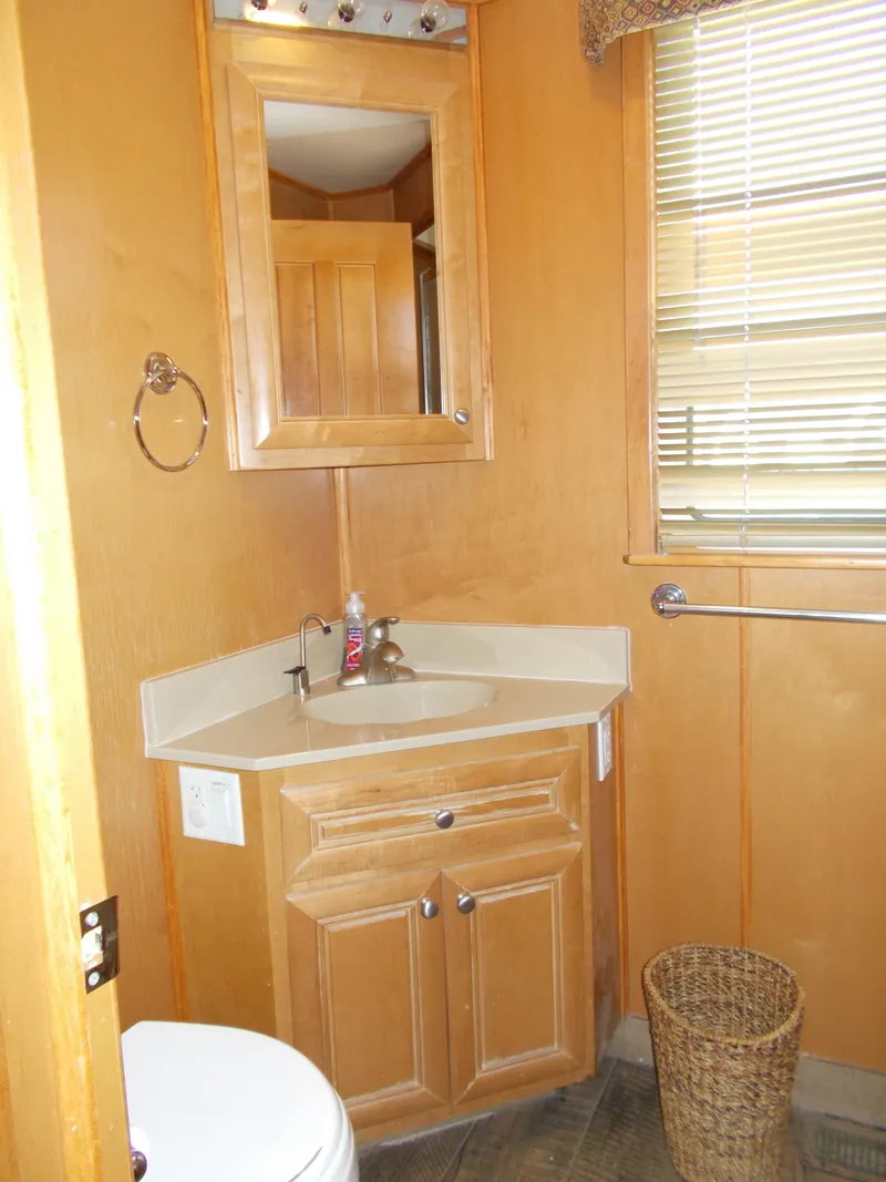 Slide: The Image of Small bathroom with wooden cabinets, corner sink, and wicker basket in a 2003 Stardust Cruisers houseboat. - 14