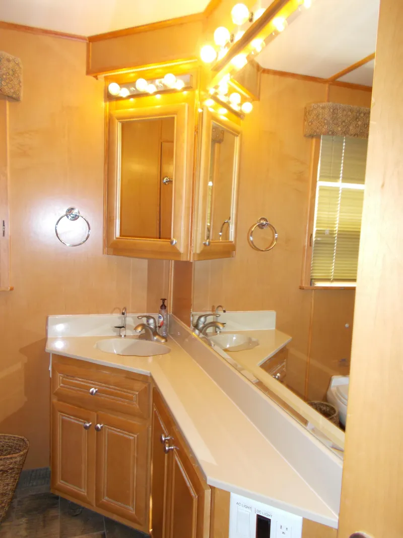 Slide: The Image of 2003 Stardust Cruisers bathroom with dual sinks, wooden cabinets, and bright vanity lights. - 21