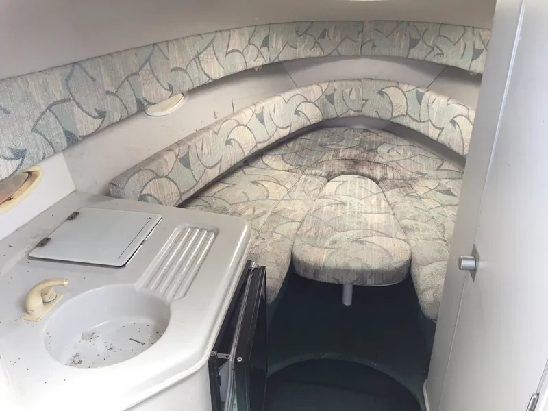 Slide: The Image of Interior of a 1992 Chris-Craft 232 Crowne boat with cushioned seating and compact kitchenette. - 3