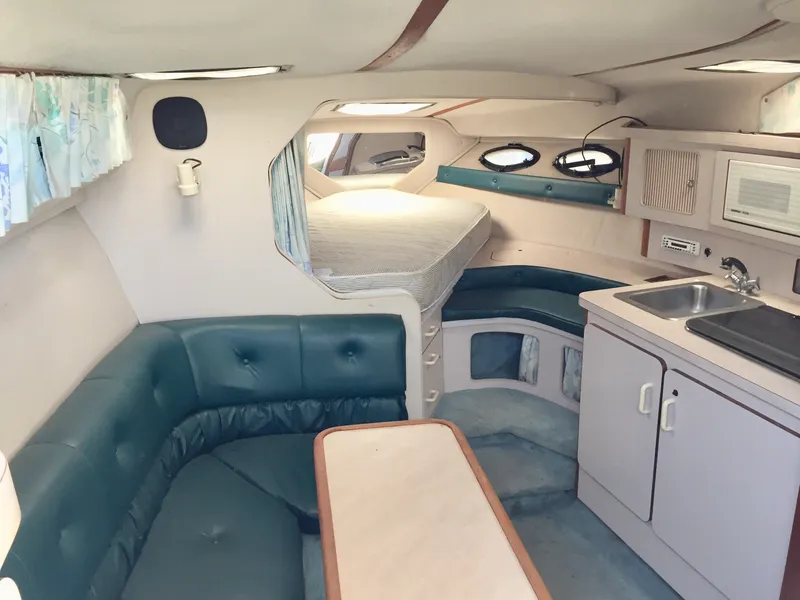 Slide: The Image of Interior of a 1993 Regal 300 Commodore boat with seating, kitchenette, and bed. - 5