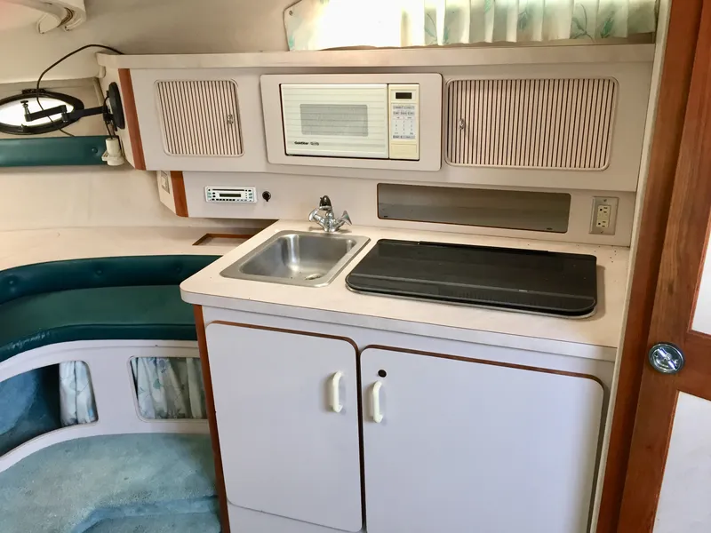 Slide: The Image of 1993 Regal 300 Commodore boat interior with kitchenette, sink, microwave, and seating area. - 7