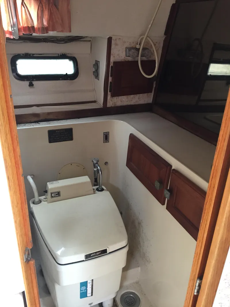 Slide: The Image of 1981 Bayliner 3250 Conquest Sunbridge boat bathroom with compact toilet and wooden cabinets. - 15