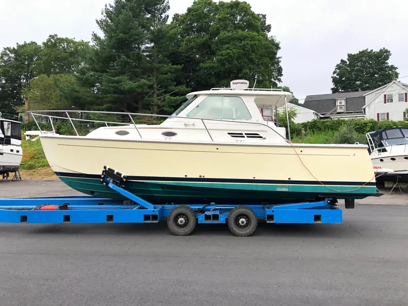 The Image of 2008 Back Cove 29 boat on blue trailer, parked outdoors near trees and houses. - 0
