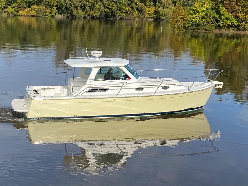 Slide: The Image of 2008 Back Cove 29 boat cruising on calm water with lush green trees in the background. - 31