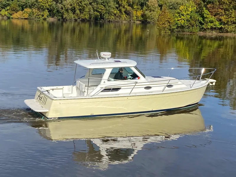Slide: The Image of 2008 Back Cove 29 boat cruising on a calm river with lush green surroundings. - 32