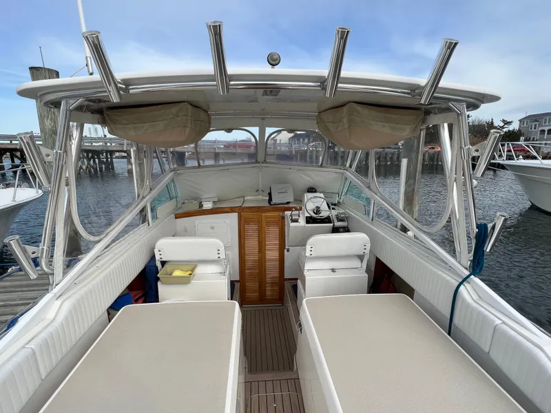 Slide: The Image of 1984 Bertram 26 Express boat interior with seating and helm, docked at marina. - 11