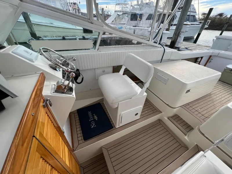 Slide: The Image of 1984 Bertram 26 Express boat interior with helm, white seating, and wooden accents. - 13