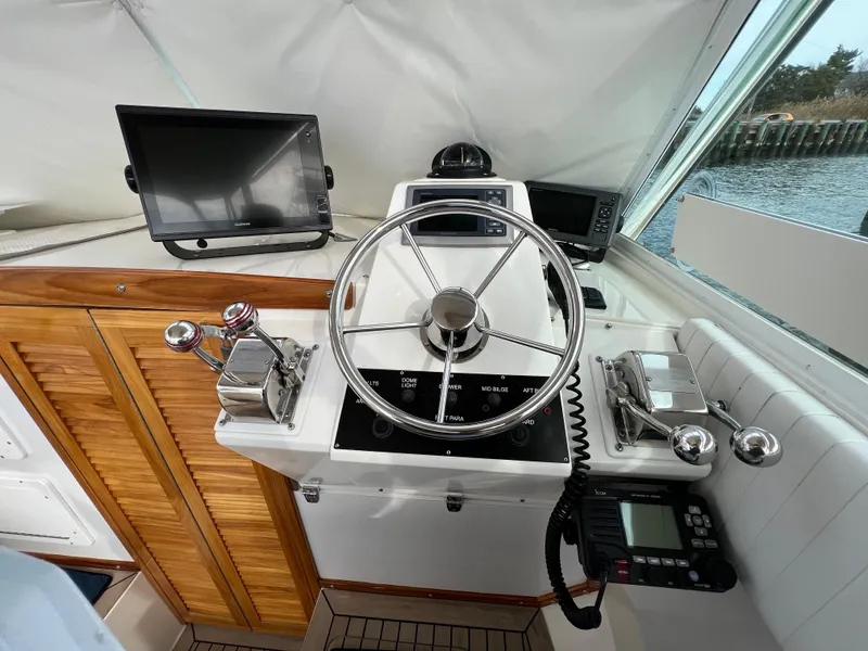 Slide: The Image of 1984 Bertram 26 Express helm with steering wheel, controls, and navigation equipment. - 16