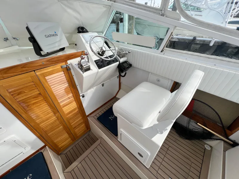 Slide: The Image of 1984 Bertram 26 Express boat cockpit with steering wheel, wooden cabinetry, and Garmin navigation system. - 18