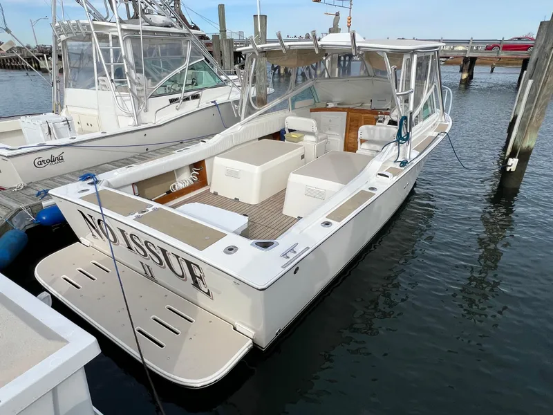 Slide: The Image of 1984 Bertram 26 Express boat docked in marina, featuring spacious deck and seating. - 2