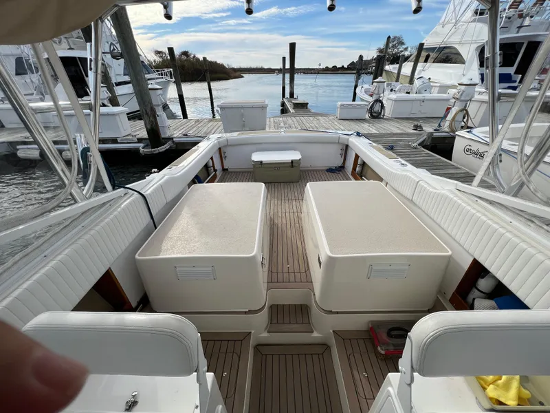 Slide: The Image of 1984 Bertram 26 Express boat interior with seating and storage, docked at a marina. - 5