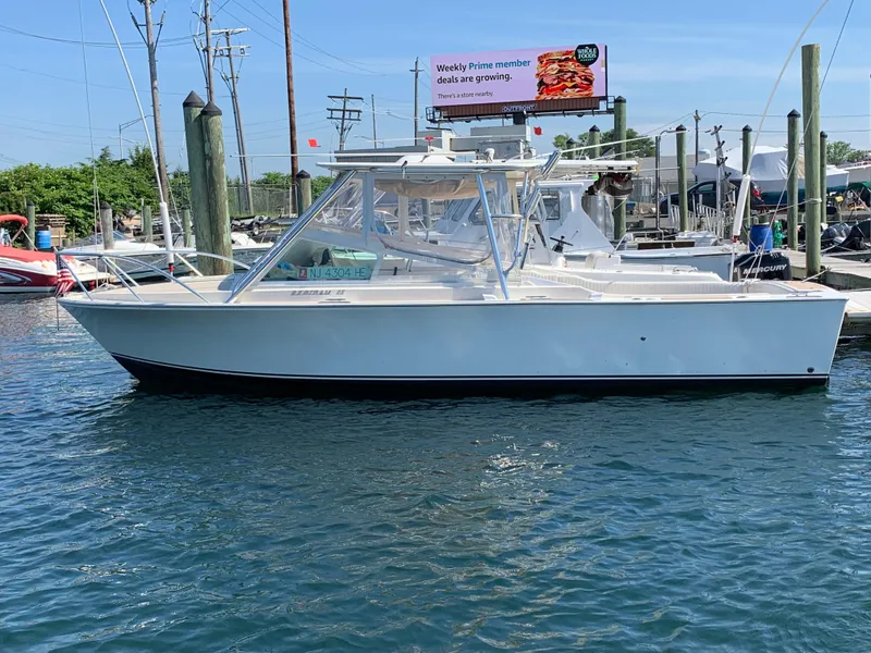 Slide: The Image of 1984 Bertram 26 Express boat docked in marina under clear blue sky. - 6