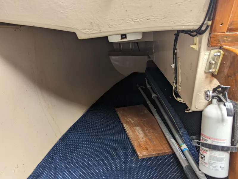 Slide: The Image of Interior of a 1987 Catalina 25 sailboat with fire extinguisher and storage. - 16