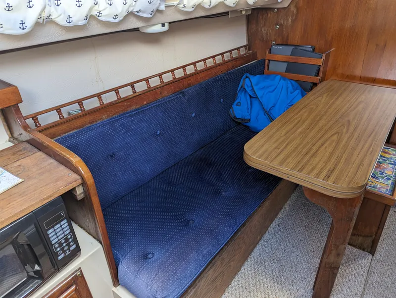 Slide: The Image of Interior of a 1987 Catalina 25 sailboat with blue cushioned seating and wooden table. - 17