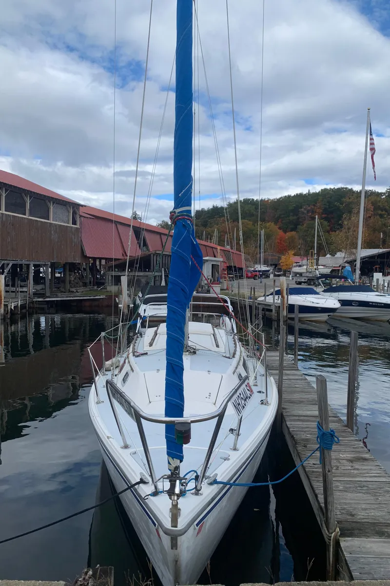 Slide: The Image of 1987 Catalina 25 sailboat docked at a marina with scenic background. - 2