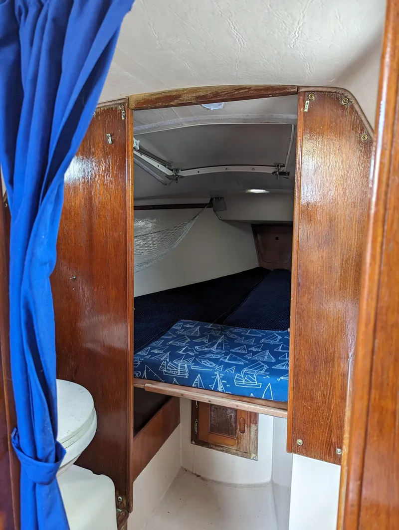 Slide: The Image of Cabin interior of a 1987 Catalina 25 sailboat with blue curtains and bedding. - 20