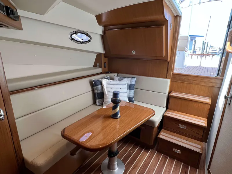 Slide: The Image of Henriques 35 Express 2025 interior cabin with dining area, wooden table, and cushioned seating. - 14