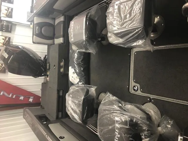 Slide: The Image of 2024 Lund 2075 Tyee boat interior with plastic-covered seats and outboard motor. - 4