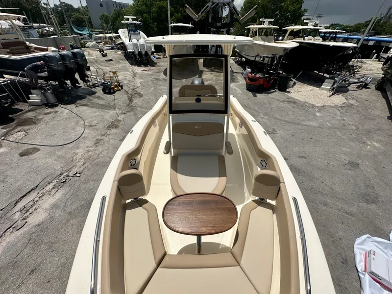 Slide: The Image of 2025 Scout 215 XSF boat interior at a marina, featuring seating and a wooden table. - 7