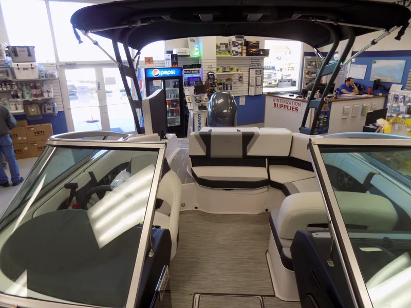 Slide: The Image of 2023 Regal 21 OBX boat interior in showroom, featuring seating and canopy. - 10