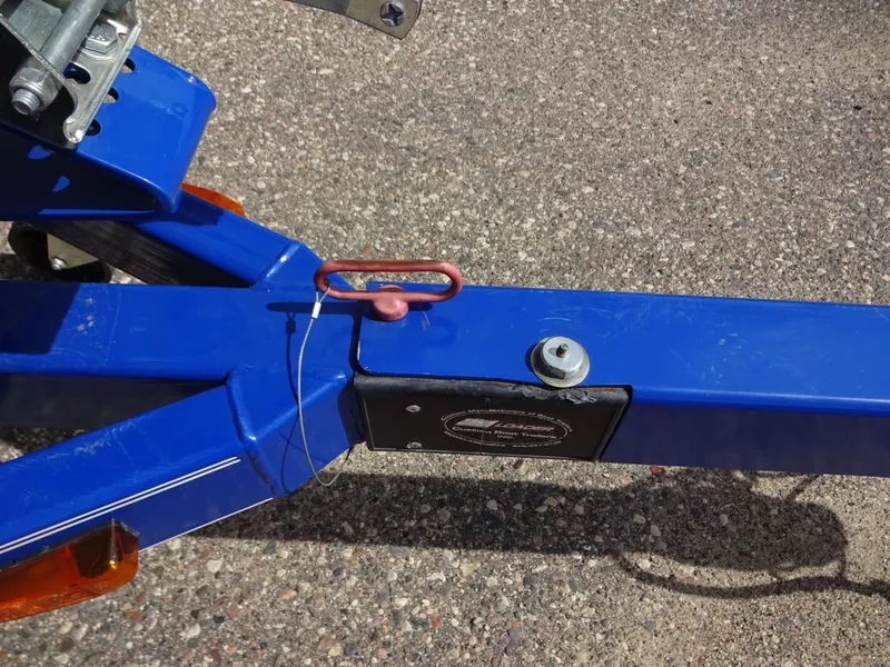 Slide: The Image of Trailer hitch of a 2005 Glastron SX195 boat, featuring a blue frame and safety pin. - 18