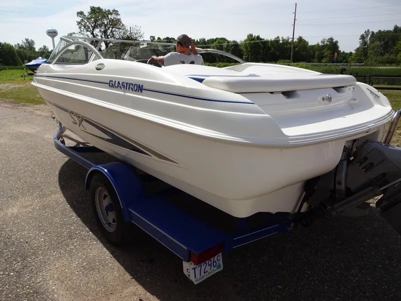 Slide: The Image of 2005 Glastron SX195 boat on trailer, parked outdoors, with a person inside. - 6