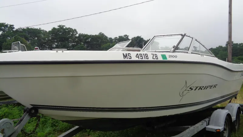 Slide: The Image of 1999 Seaswirl Striper 21 DC boat on trailer, side view, white hull, outdoors. - 13