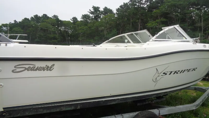 Slide: The Image of 1999 Seaswirl Striper 21 DC boat on trailer, side view with forest background. - 14