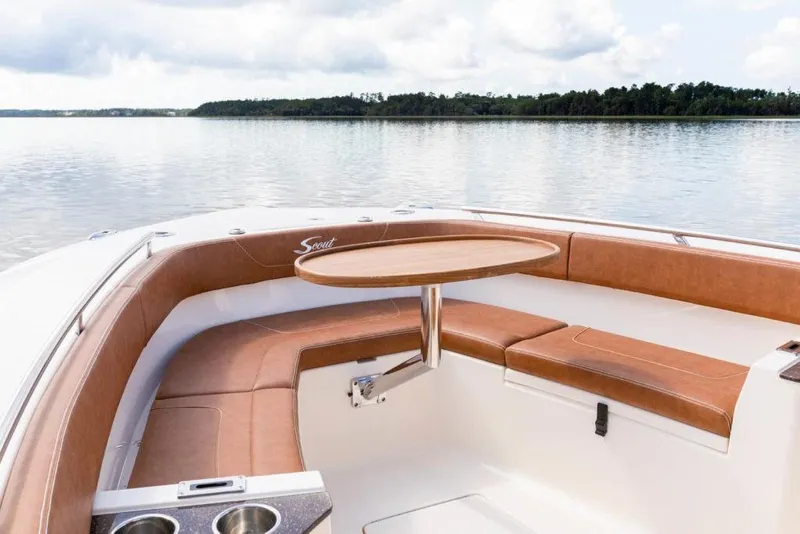 Slide: The Image of 2023 Scout 277 LXF boat with brown seating and a round table on calm water. - 12