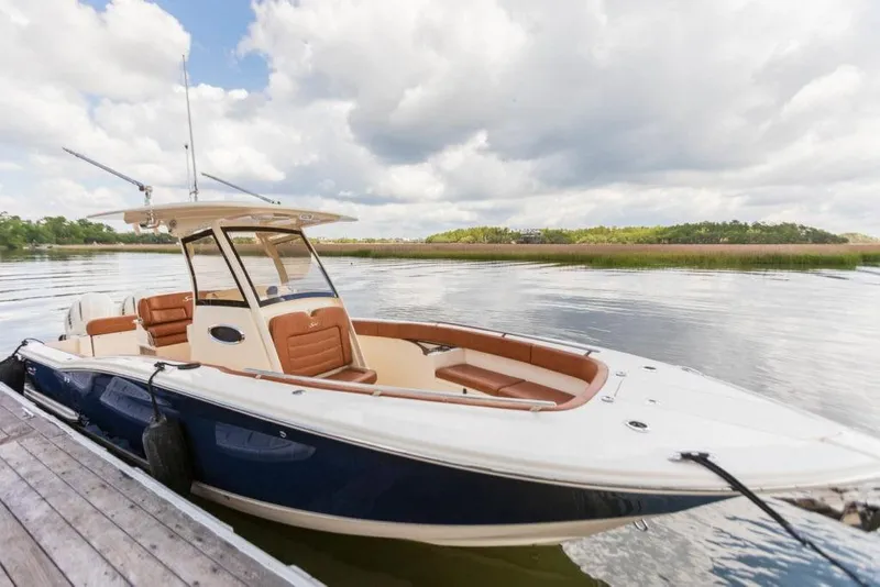 Slide: The Image of 2023 Scout 277 LXF boat docked on a calm lake under a cloudy sky. - 7